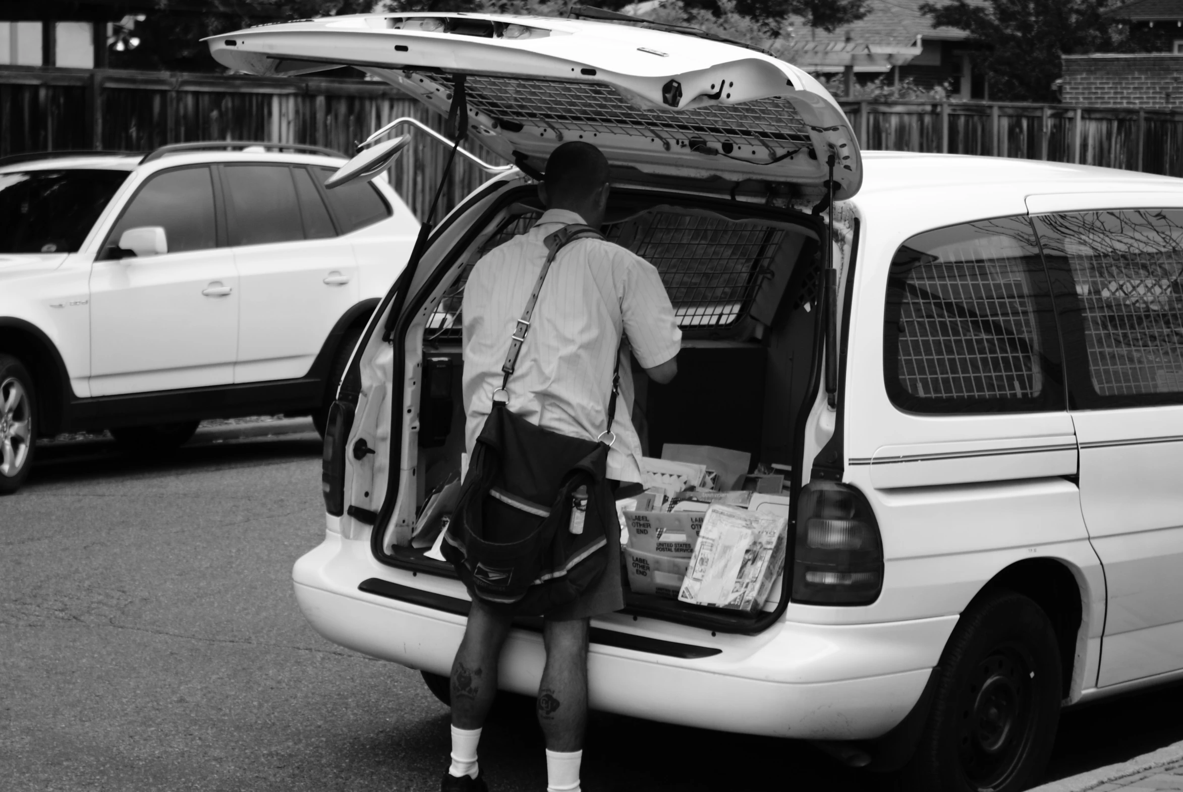 a white van with the back door open and its hatch open and two people sitting inside it