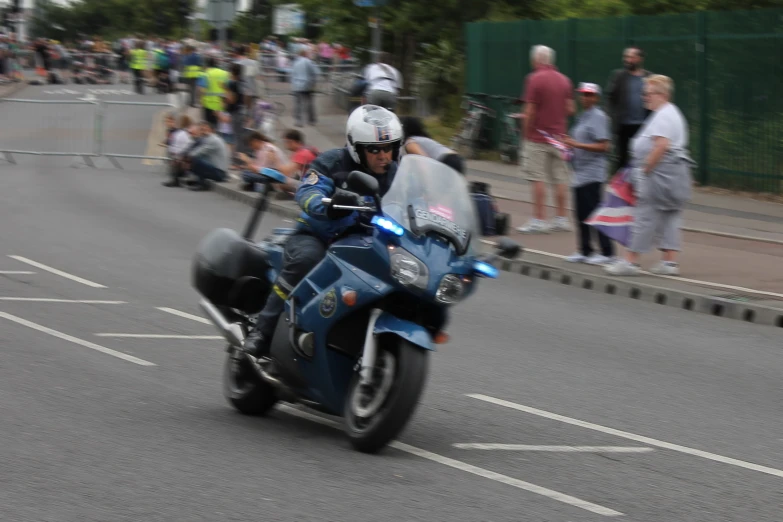 a man riding a blue motorcycle down the street