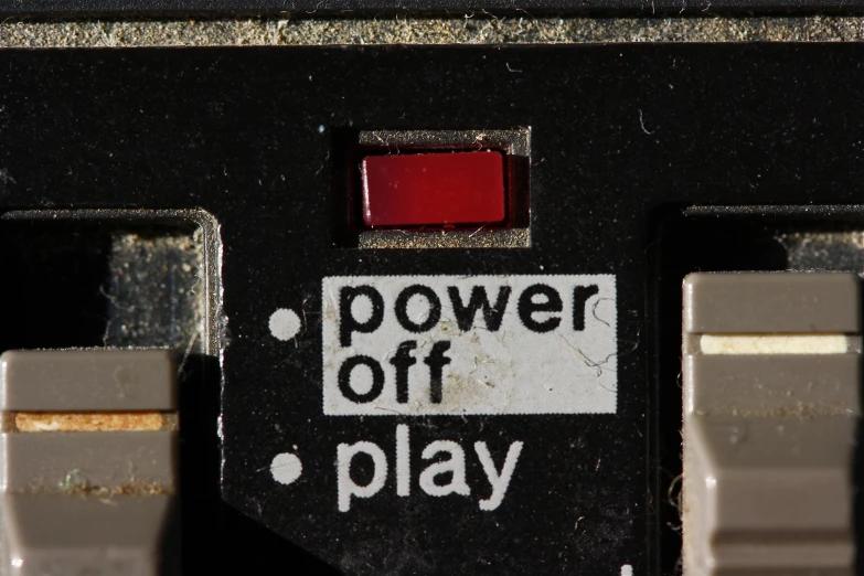 a black device with a red on and a white sign that says power off play
