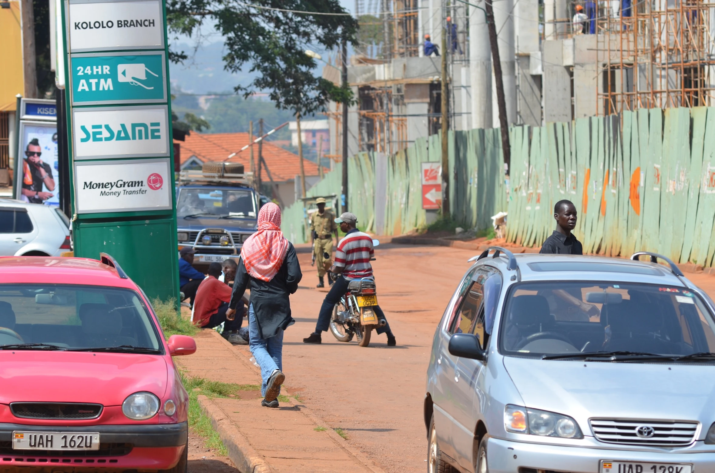 some cars are traveling down a road and people are walking