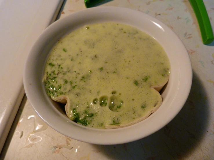 a white bowl of soup sitting on top of a  board