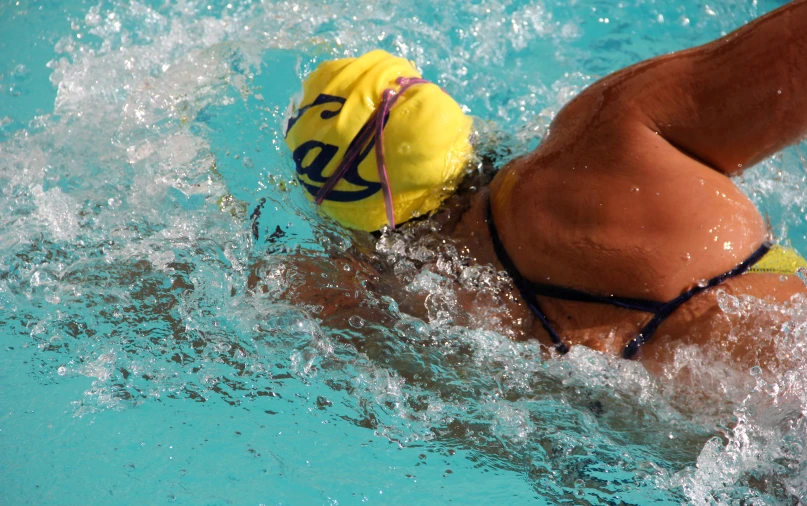 a woman wearing a hat and swimming in a pool