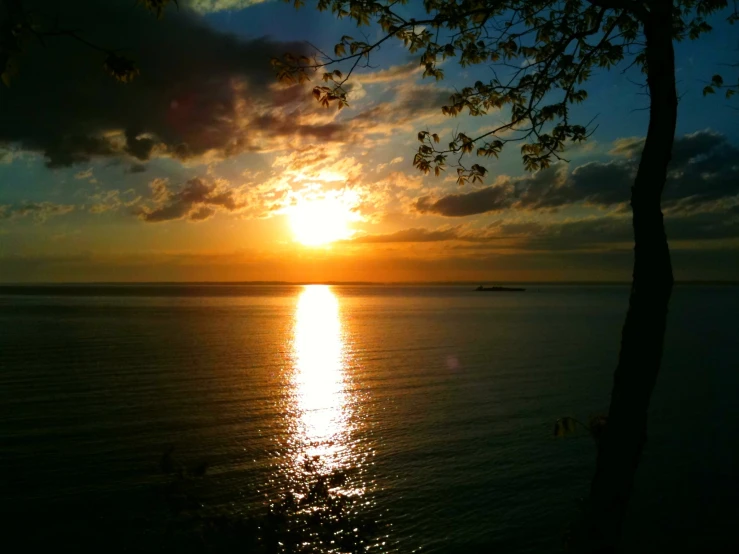 a sunset and water are seen behind some clouds