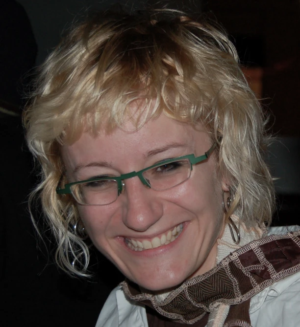 a lady with glasses smiles while wearing a scarf