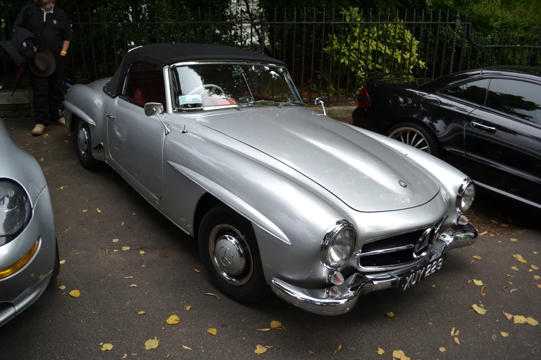 the classic car is parked on the street with the woman beside it