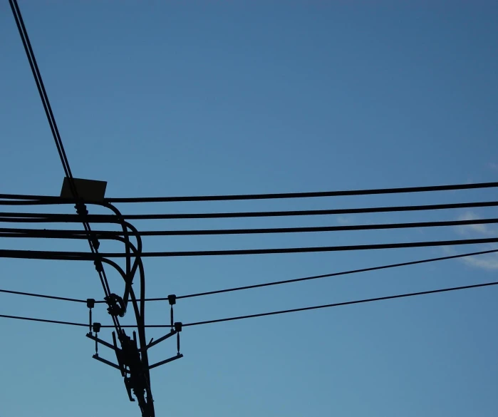 an electric tower with lots of wires against the sky