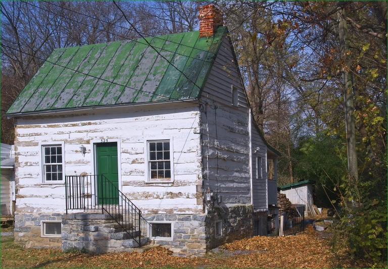 a dilapidated old brick building has a green door and small window