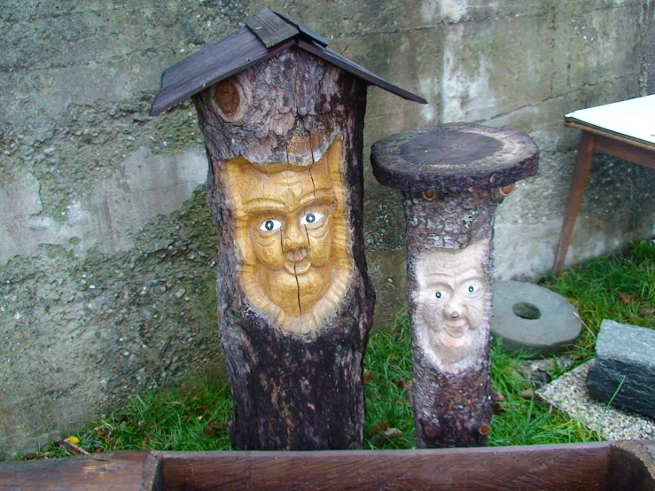 two wood carving depicting cats and their own heads are shown near a house