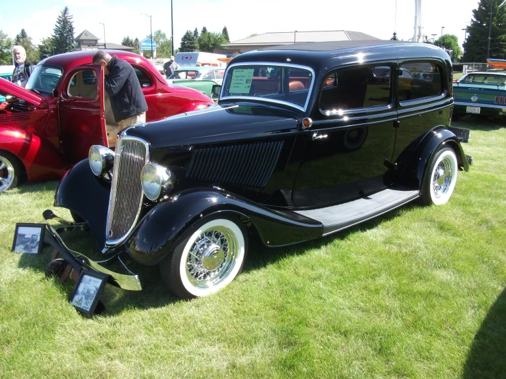 a black classic car is parked in the grass