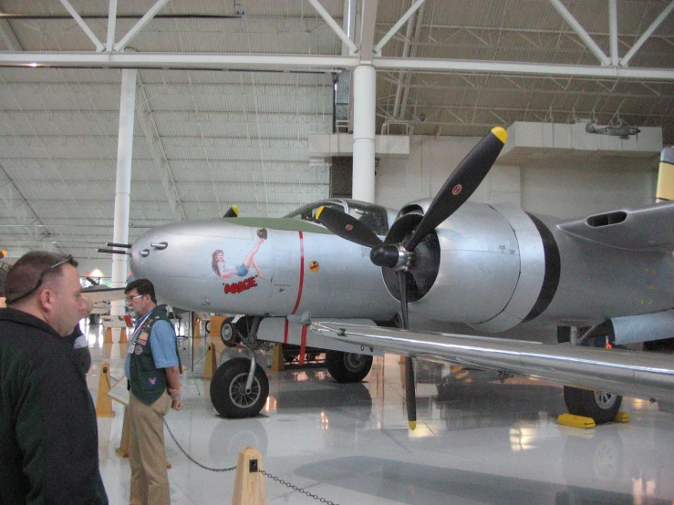 an old plane in a hanger with some people looking at it