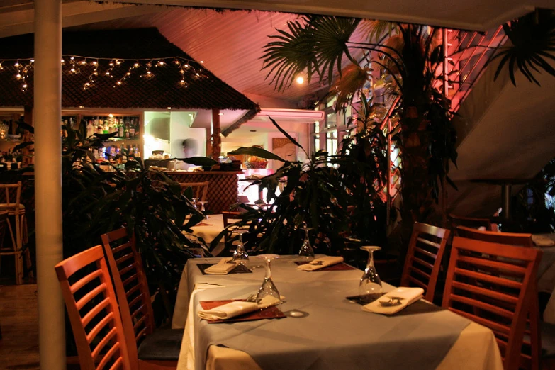 a restaurant with white table cloths and hanging plants