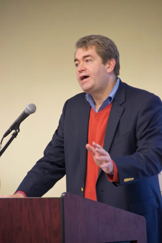 man in business suit speaking at podium with microphone