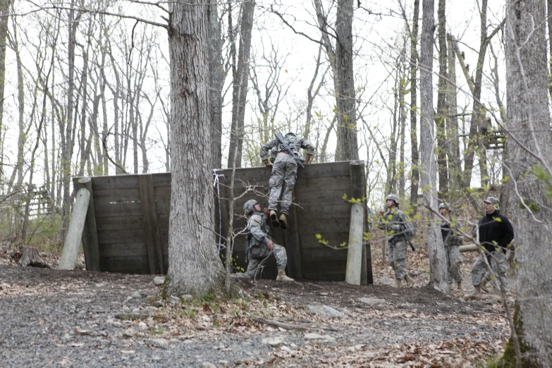 soldiers going through an obstacle while their dog watches