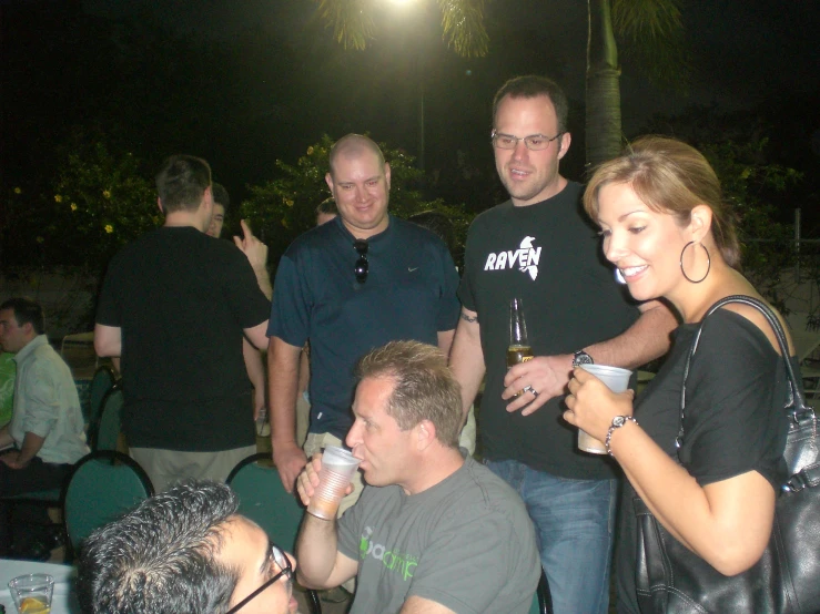 a group of people standing around a table drinking