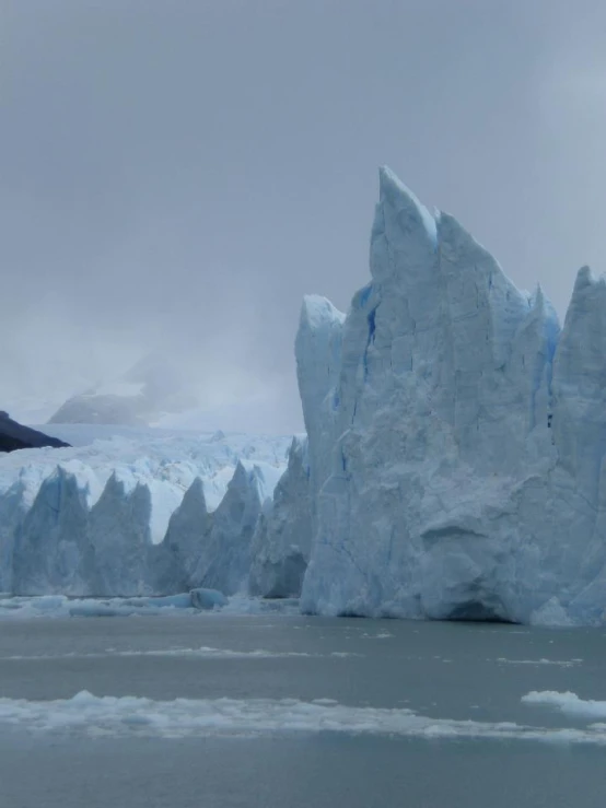 a large iceberg towering over a city on a cloudy day