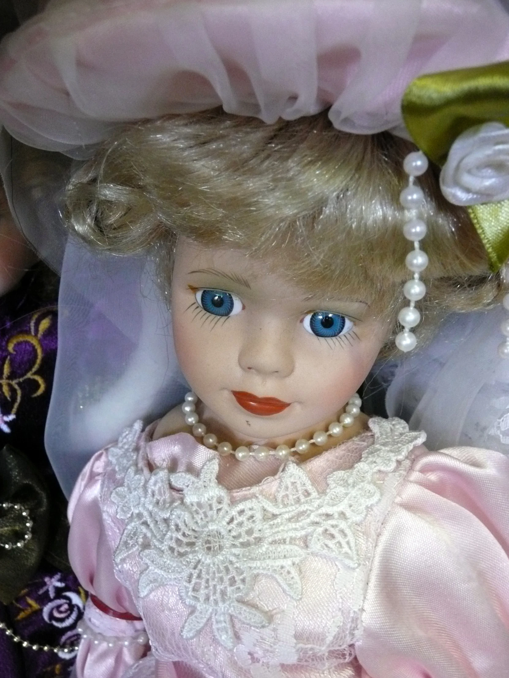 a white stuffed doll wearing pearls and pink dress