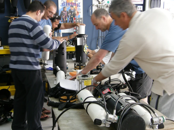 three men in a factory working on robot bodies