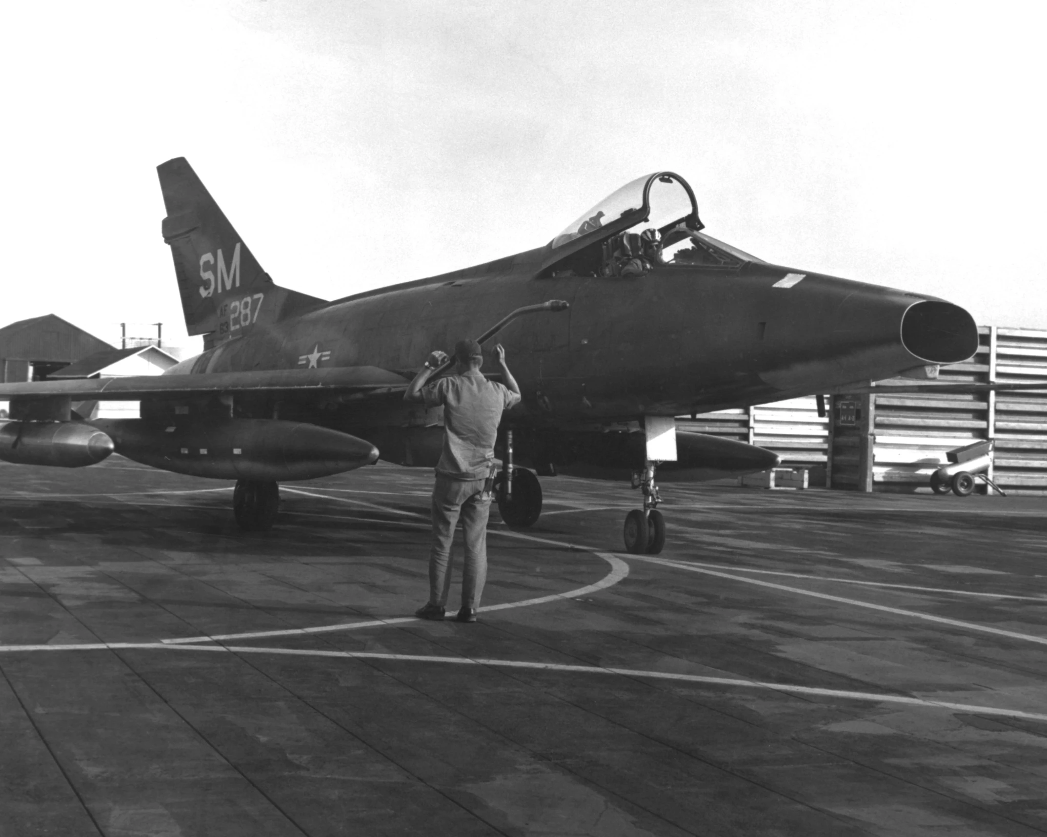 a man standing in front of an air force jet on an airport tarmac