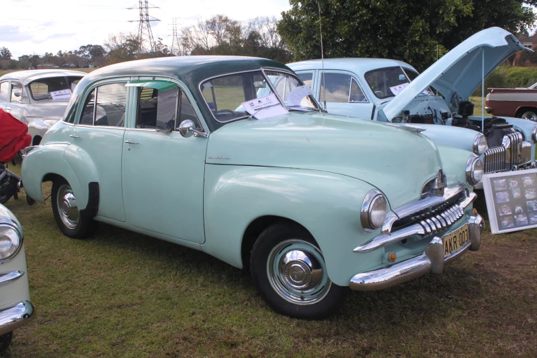 classic cars displayed in a field and two people are taking pictures