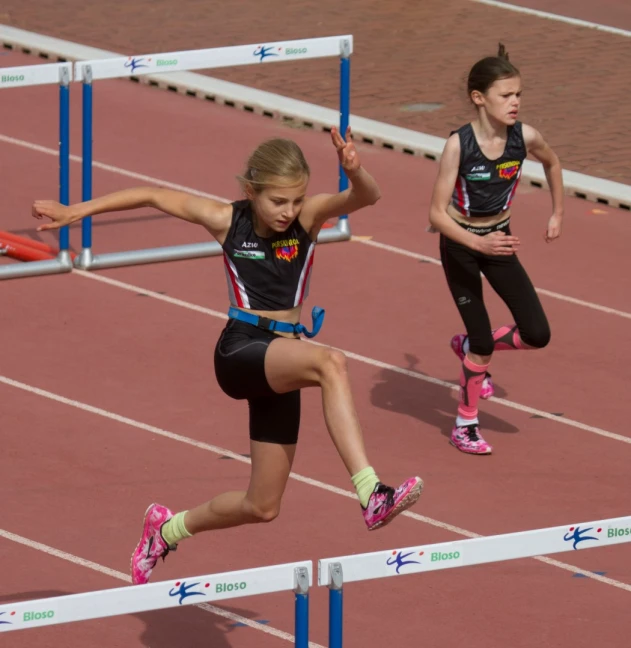 girls wearing black sports clothing and running in a track