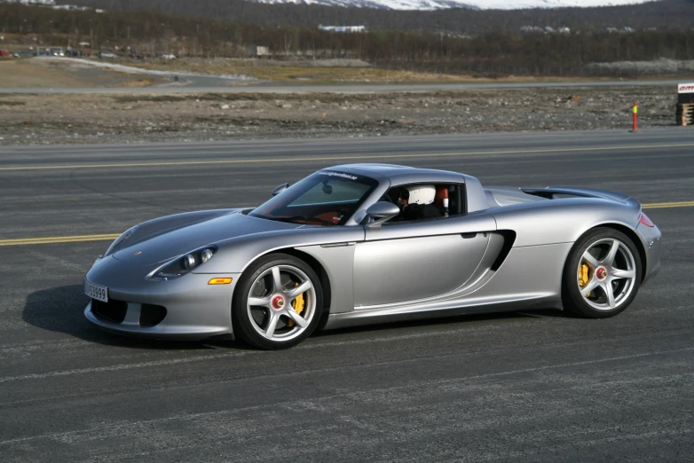 a silver sports car drives through the rural area