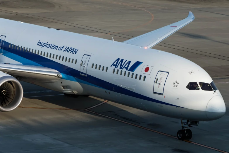 an ana airplane parked on the runway with a red tail