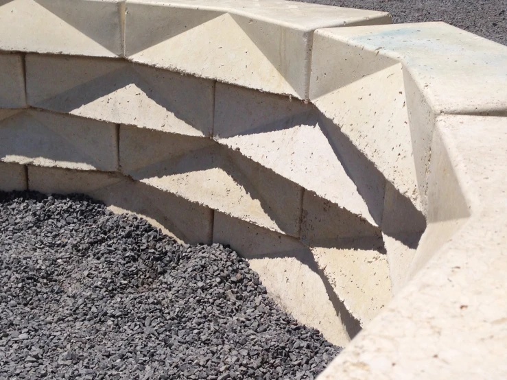 a cement bench has no seat and is on concrete gravel