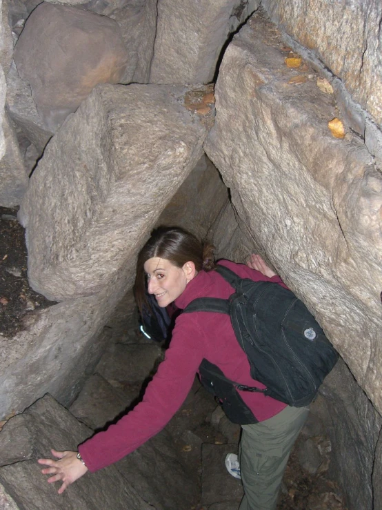 a woman with a backpack is posing in an underground pit