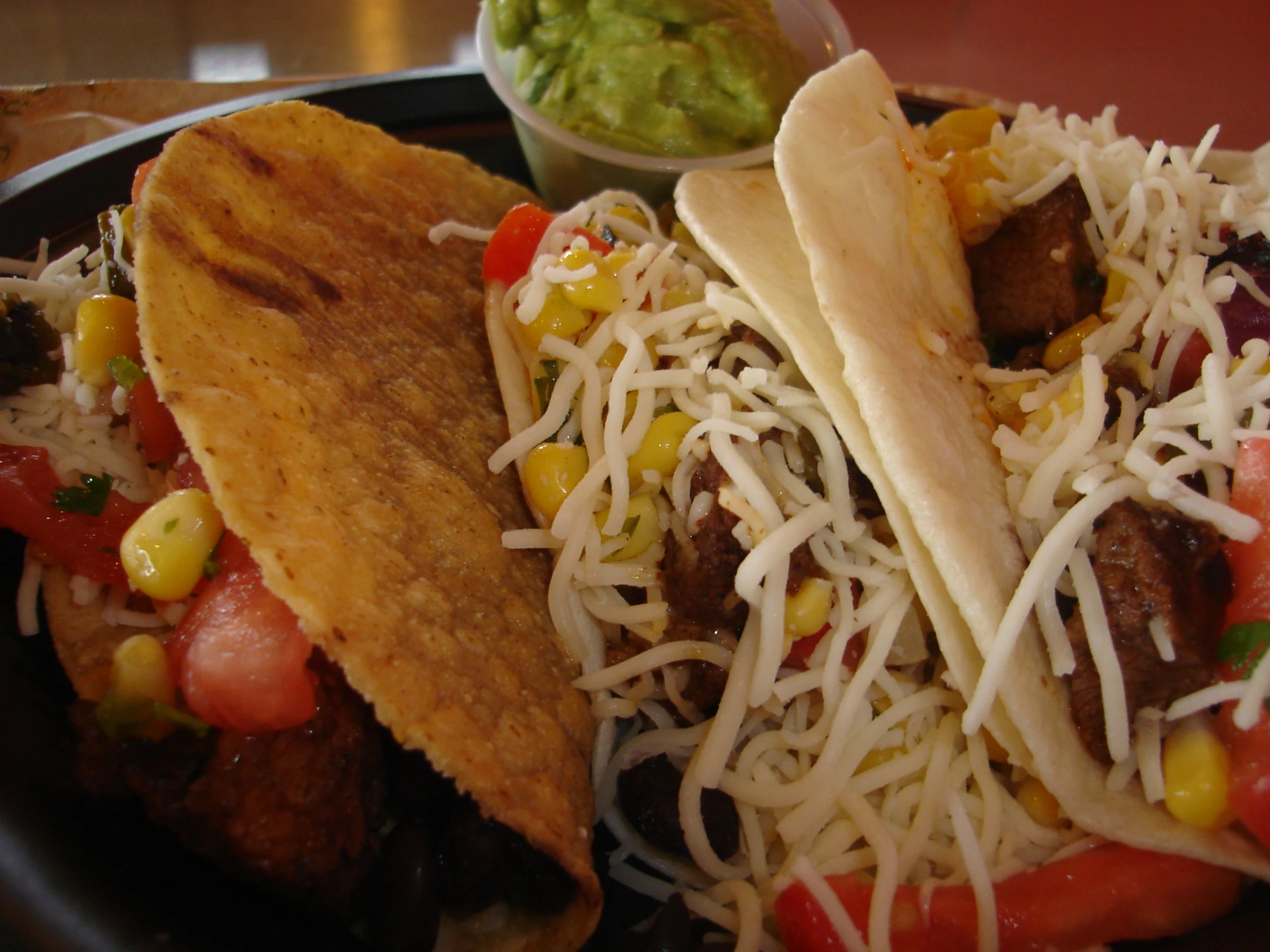 some tacos and chips sit on a plate with salsa