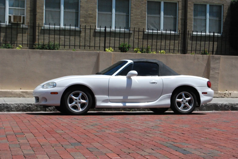 a car with a white top and white wheels parked in a city street