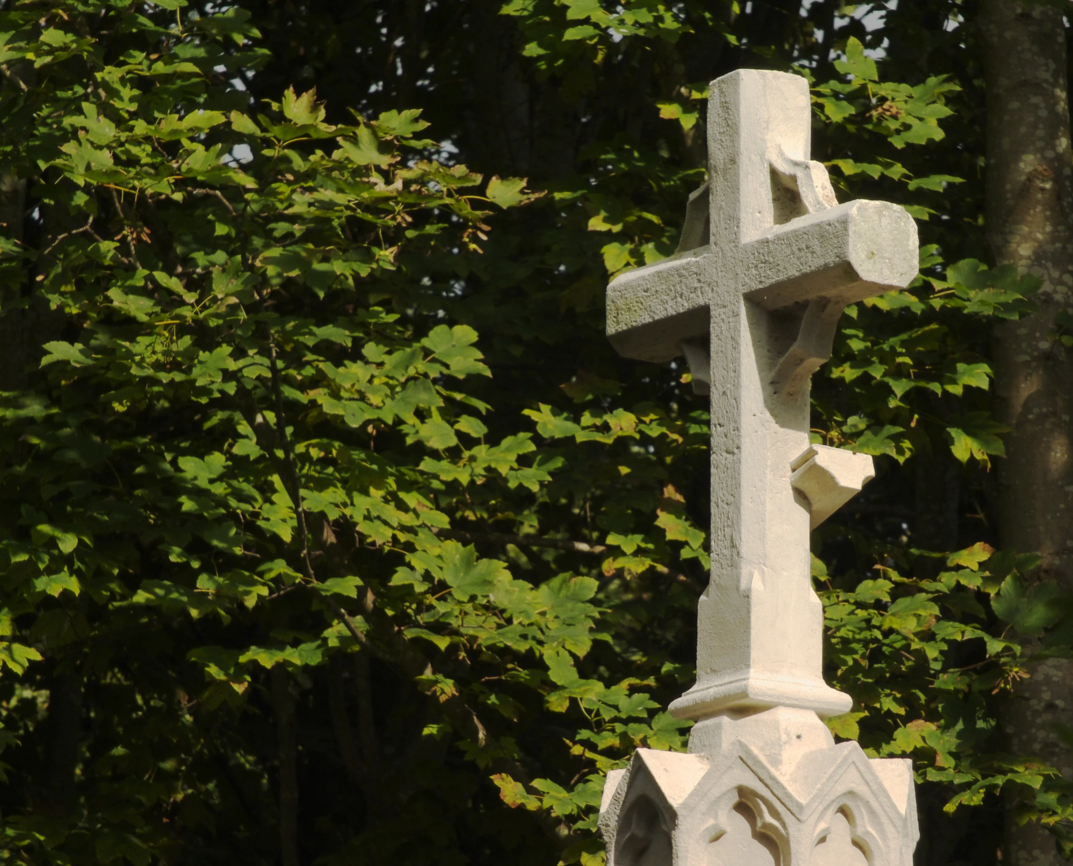 the white cross on the side of the building in front of the trees