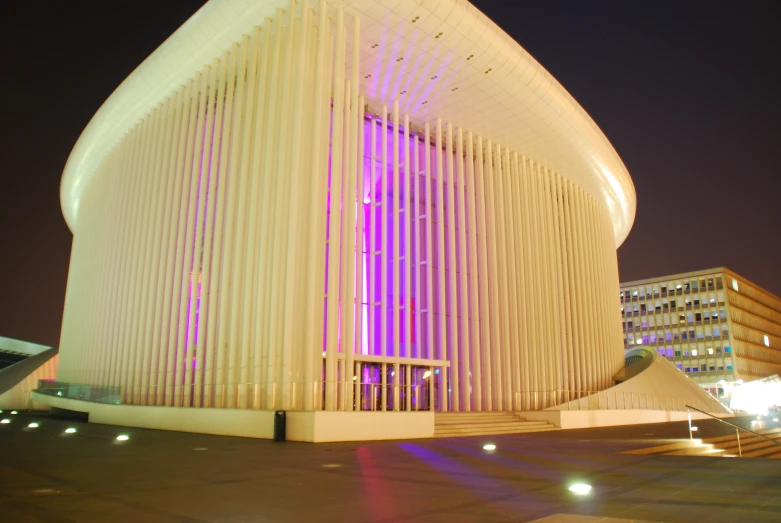 an unusual building with pink lighting shining from outside