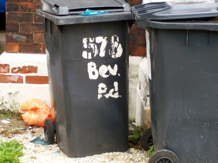 two trash cans sitting on the ground beside each other