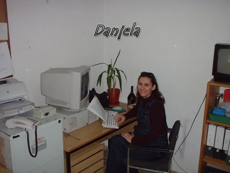 a woman sitting at a desk with a small computer