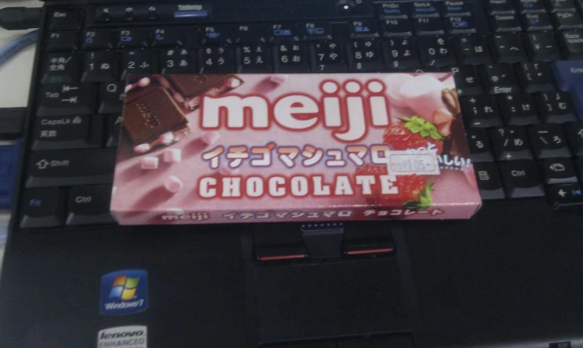 a chocolate bar wrapped in japanese wrapping sits atop a laptop keyboard