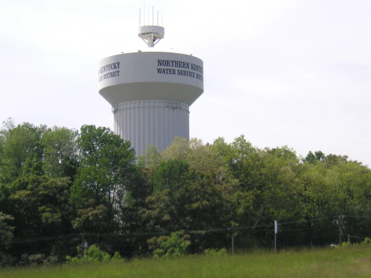 a water tower is standing above some trees