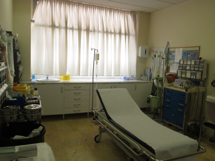 an empty hospital bed near two windows
