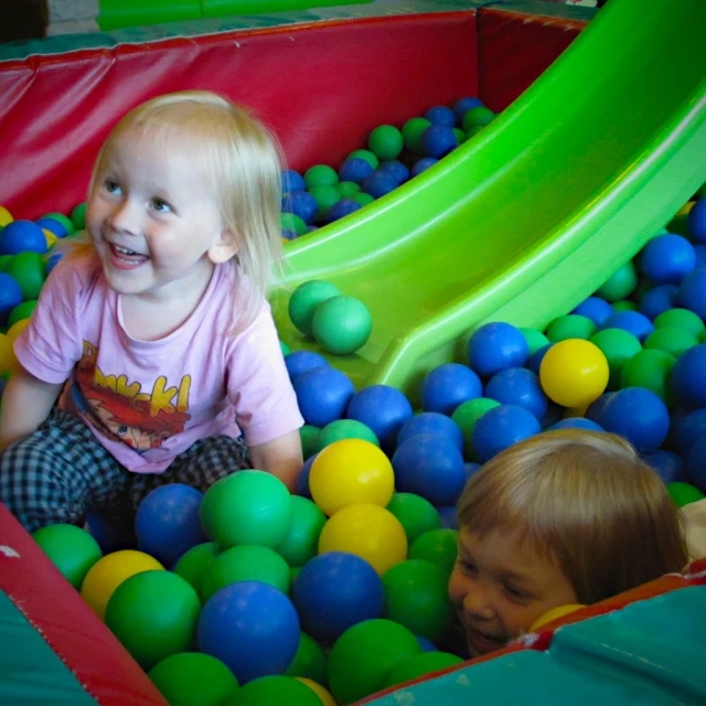 there are two little girls playing in the ball pit