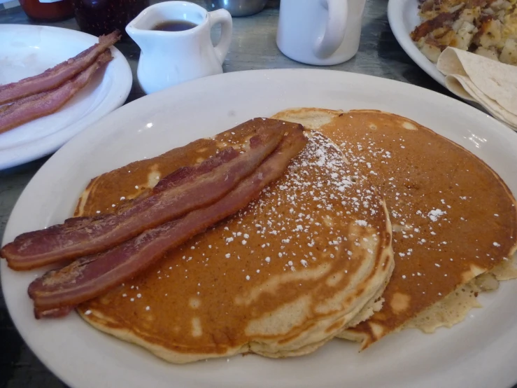 pancakes are served on plates with bacon