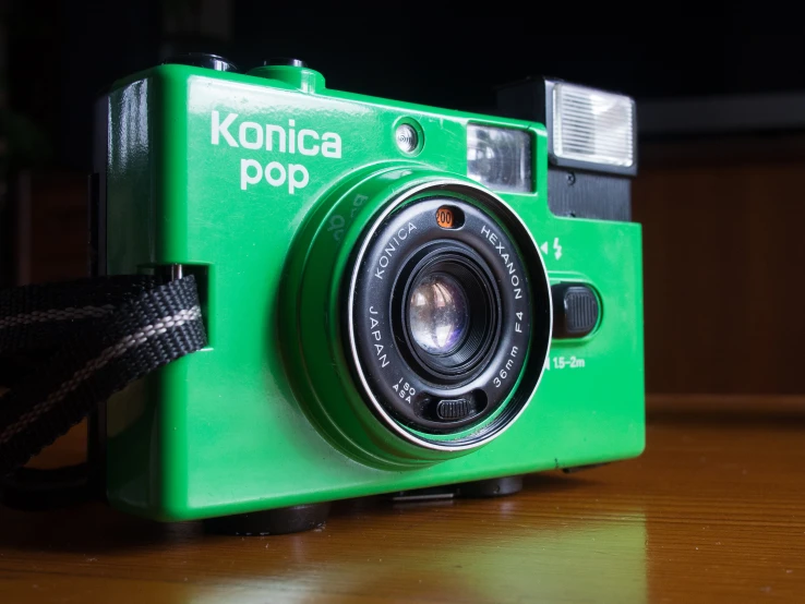 a green camera with black lens on top of a wooden table