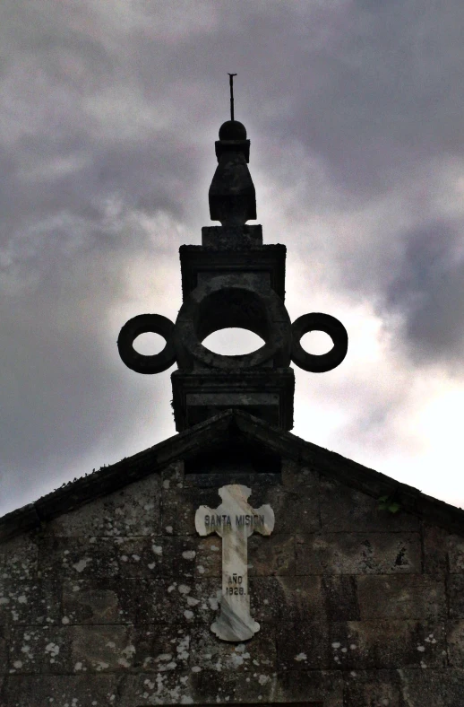 the top of an old building has a cross and an eye on it