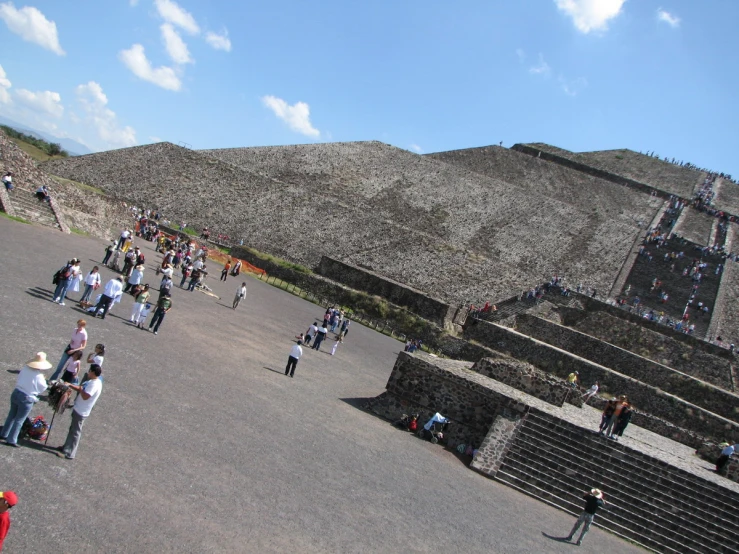 many tourists walking down a walkway to get to some interesting structures