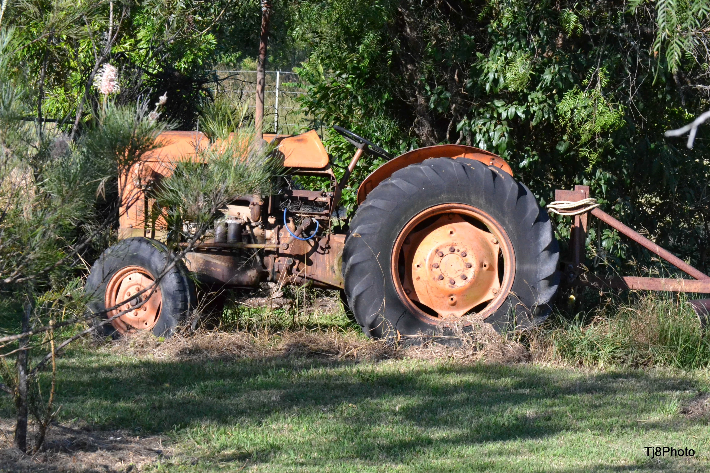 an old rusted out tractor stands still in a field