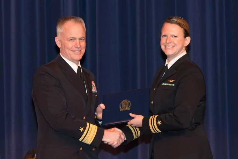 two uniformed people shaking hands on stage