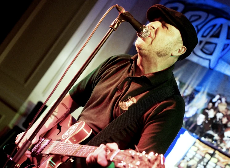 a man singing into a microphone while playing guitar