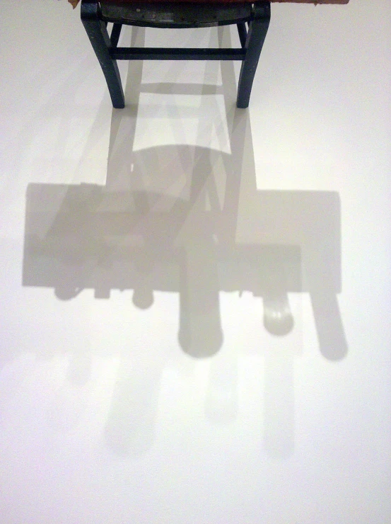 shadow of the seat and foot rest of a wooden bench on a white wall