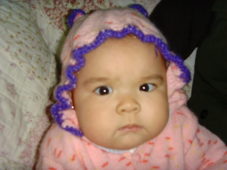 a small baby girl wearing a crocheted hat and pajamas