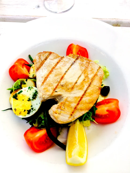 a fancy white plate contains meat and vegetables