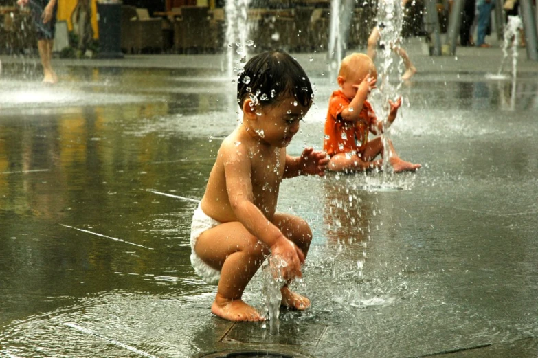 a little boy sitting down in the water playing with it