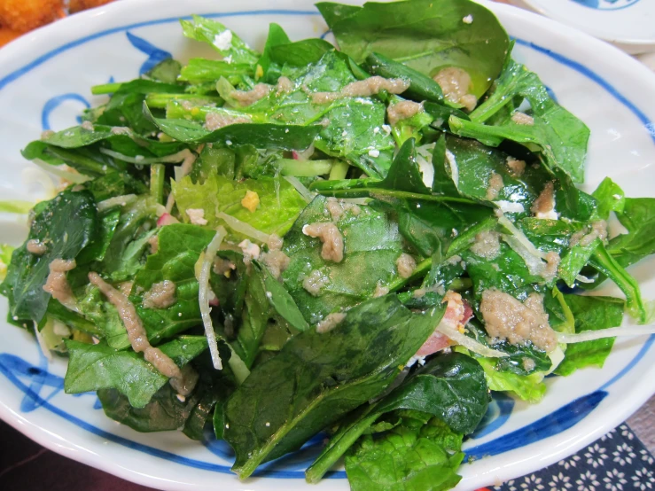 a plate is filled with leafy greens next to some meat